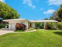 Charming single-story home boasts vibrant landscaping and a welcoming red front door at 302 Mendez Dr, Sarasota, FL 34243