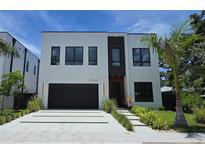 Modern two-story home with a black garage door, clean lines, and well-manicured landscaping at 3464 Camino Real, Sarasota, FL 34239