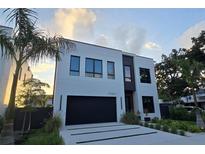 Contemporary two-story home featuring a black garage door, modern windows, and minimalist landscaping at 3464 Camino Real, Sarasota, FL 34239