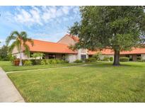 Beautiful single-story home showcasing a well-maintained lawn, mature trees, and a charming orange tiled roof at 6384 Draw Ln # 38, Sarasota, FL 34238