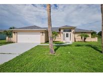 Tan house with a white door, two-car garage and palm trees at 13592 Clara Ln, Port Charlotte, FL 33981