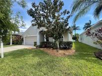 Tan house with a two-car garage and manicured lawn at 1822 Raven Glen Dr, Ruskin, FL 33570