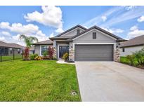 One-story home with gray exterior, landscaped lawn, and two-car garage at 16162 61St E Ln, Parrish, FL 34219