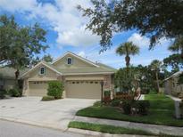 Tan two-car garage villa with lush landscaping at 4939 Lakescene Pl, Sarasota, FL 34243