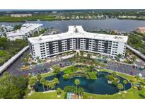 Aerial view of a condo building with a pond and parking at 5855 Midnight Pass Rd # 420, Sarasota, FL 34242