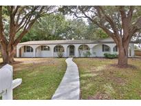 Charming single-story home with an arched entryway, a well-manicured lawn, and mature trees creating a picturesque setting at 2912 Pinecrest Way, Sarasota, FL 34239