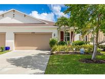 Tan house with two-car garage, landscaping, and Buddha statue at 8798 Tuscany Isles Dr, Punta Gorda, FL 33950