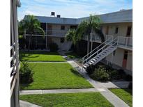 Exterior view of an apartment building with a grassy courtyard at 400 Base E Ave # 229, Venice, FL 34285