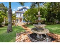 Charming two-story blue home featuring a brick walkway to a tiered water fountain and a well-manicured lawn at 1332 3Rd W Ave, Bradenton, FL 34205