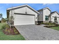 Beautiful home featuring a spacious garage, manicured landscaping, and an inviting paver driveway at 18773 Dayspring Pl, Venice, FL 34293