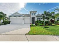 Modern home exterior with three-car garage and lush landscaping at 12734 Rainwashed Loop, Parrish, FL 34219