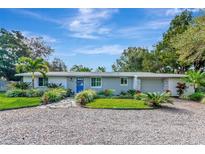 Gray brick ranch house with a blue door, landscaping, and gravel driveway at 2244 Palm Ter, Sarasota, FL 34231