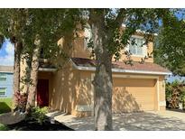 Two-story tan house with red door, attached garage, and landscaping at 7078 Chatum Light Run, Bradenton, FL 34212