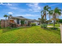 Single story home with a large green lawn, palm trees, and fenced backyard at 3917 Cochise Ter, Sarasota, FL 34233