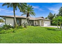 Single-story home with a two-car garage and lush landscaping at 10194 Thames Ave, Englewood, FL 34224