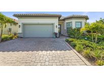 Inviting home featuring a two-car garage, beautiful landscaping, and a brick-paved driveway at 14480 Eagle Branch Dr, Nokomis, FL 34275