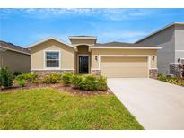 Tan house with stone accents, two-car garage, and manicured lawn at 12354 Nantahala Run, Parrish, FL 34219
