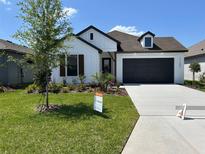 Charming home with modern farmhouse design, dark trim, manicured lawn and landscaping, and a concrete driveway at 11709 Capstan Pl, Parrish, FL 34219