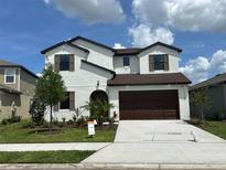Charming two-story stucco home featuring a well-manicured lawn, arched entry, and a two-car garage at 11722 Capstan Pl, Parrish, FL 34219