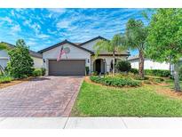 Charming single-Gathering home featuring a well-manicured lawn, brick driveway, and a two-car garage at 7572 Viola Loop, Lakewood Ranch, FL 34202
