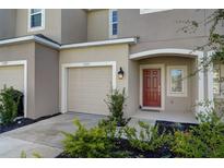 Townhouse with attached garage and a red front door at 5725 Haven Ter, Nokomis, FL 34275