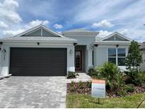 Charming single-story home featuring a well-manicured lawn, brick driveway, and a two-car garage with a stylish red front door at 766 Hillshire Pl, Spring Hill, FL 34609