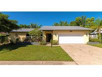 Well-maintained home with a metal roof, large driveway, and mature landscaping at 1544 Palmwood Dr, Sarasota, FL 34232