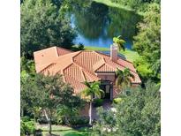 Beautiful aerial view of a house with a tile roof surrounded by lush greenery and overlooking a tranquil pond at 14636 Newtonmore Ln, Lakewood Ranch, FL 34202