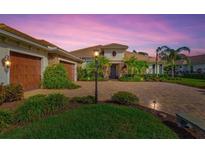 Elegant home entrance with a paver driveway and well manicured landscaping at dusk at 1111 143Rd Ne St, Bradenton, FL 34212