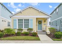 Quaint yellow cottage with light blue shutters and welcoming porch at 12622 Shimmering Oak Cir, Venice, FL 34293