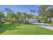 Single-story house with landscaped yard, palm trees, and a brick driveway at 21 Bayhead Ln, Osprey, FL 34229