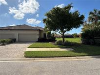 Tan two-car garage villa with lush landscaping and paved driveway at 8191 Varenna Dr, Sarasota, FL 34231