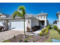 Tan house with white garage door and landscaping at 251 Okeeffe Cir, Bradenton, FL 34212