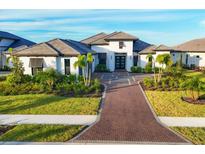 Modern home exterior with a paver driveway and lush landscaping at 1209 Blue Shell Loop, Sarasota, FL 34240