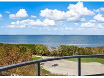 Expansive water view from the balcony overlooking lush greenery and a golf course, set against a backdrop of blue sky and clouds at 3070 Grand Bay Blvd # 632, Longboat Key, FL 34228