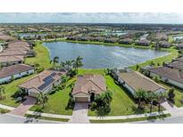 Stunning aerial view of a lakeside community with well-maintained lawns and beautiful tile-roofed homes at 6547 Willowshire Way, Bradenton, FL 34212