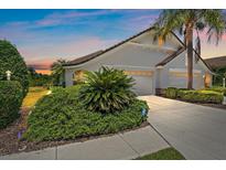 Beautiful home featuring a well-manicured lawn, tropical foliage, and a two-car garage at 7011 Woodmore Ter, Lakewood Ranch, FL 34202