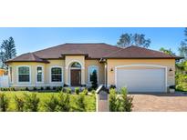 Inviting single-story home featuring a manicured lawn, arched entryway, brick driveway, and attached garage at 1900 Colleen St, Sarasota, FL 34231