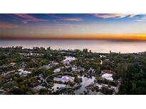 Sunset aerial view of waterfront estate featuring a private boat dock, pool, and lush tropical landscaping at 1243 Starboard Ln, Sarasota, FL 34242