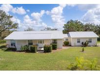 Charming single-story home with a well-maintained lawn, metal roof, and inviting front porch at 38603 Taylor Rd, Myakka City, FL 34251