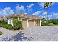 Stunning home showcasing lush landscaping, a paver driveway, a barrel tile roof, and a three-car garage at 10209 Discovery Ter, Bradenton, FL 34212