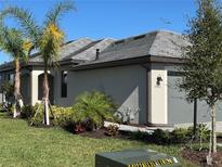 Single-story home with gray exterior, landscaped yard, and palm trees at 15511 Sunny Day Dr, Lakewood Ranch, FL 34211