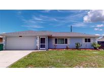 Light blue house with a grey roof, two-car garage, and well-maintained lawn at 20439 Peachland Blvd, Port Charlotte, FL 33954