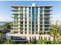 A modern condo building with floor to ceiling windows and balconies on a sunny day near the water at 111 Golden Gate Pt # 602, Sarasota, FL 34236
