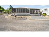 Mobile home with screened porch and gravel driveway at 2107 Palma Sola Blvd # 94, Bradenton, FL 34209