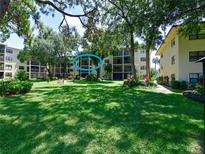 Exterior view of condo building with lush landscaping and a tranquil lake at 315 30Th W Ave # B311, Bradenton, FL 34205