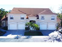 Tan three-unit building with tile roofs, three-car garage, and lush landscaping at 7225 Cedar Hollow Cir # 20-201, Bradenton, FL 34203