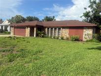 Charming single-story home featuring a stone facade, lush green lawn and a brown garage door at 117 Hillcrest Dr, Bradenton, FL 34209