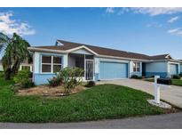 Front view of a light blue house with a two-car garage and well-maintained lawn at 3115 Live Oak Ln # 30, Palmetto, FL 34221