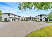 Stunning white home with black trim, multi-car garage, circular driveway, and manicured landscaping at 2410 Slough Rd, Sarasota, FL 34240